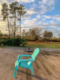 Empty chairs and tables by swimming pool against sky
