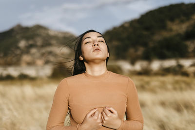 Beautiful woman with eyes closed standing in field during sunset