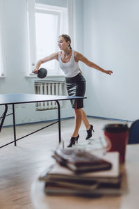 Full length of businesswoman playing tablet tennis in office