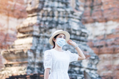 Portrait of young woman standing against built structure