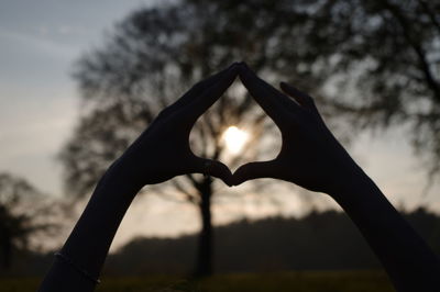 Close-up of silhouette hands making heart shape during sunset