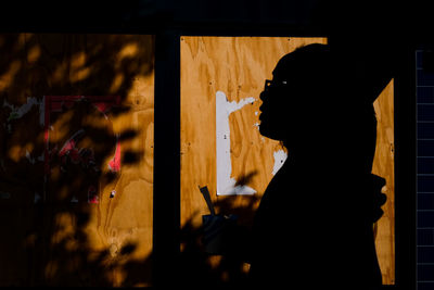 Side view of woman walking boarded up shop