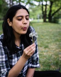 Close-up of woman holding dandelion seed outdoors