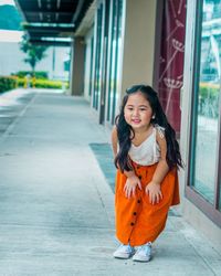 Portrait of smiling girl standing against orange wall