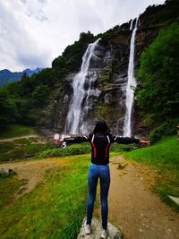 Rear view of man standing against waterfall