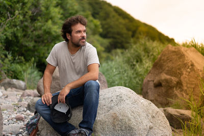 Young man sitting on rock