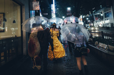 People walking on illuminated street at night