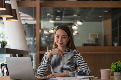 Portrait of young woman sitting on table
