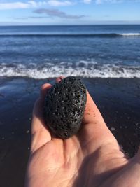 Close-up of hand holding stone at beach