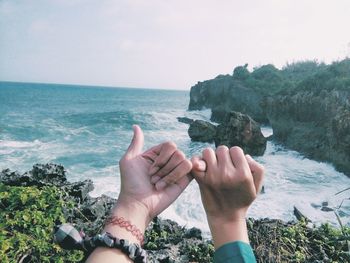 Cropped hands of couple against sea