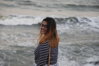 Portrait of smiling young woman standing against sea