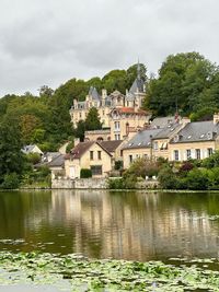 Houses by lake against sky