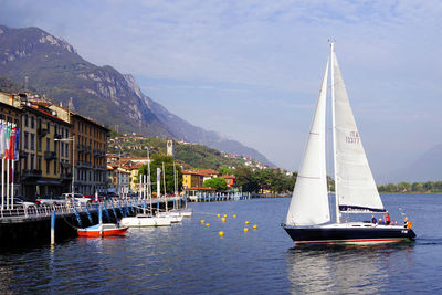 Sailboat sailing on sea by buildings against sky