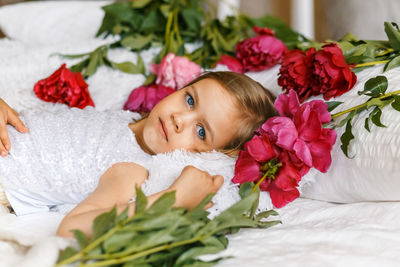Portrait of girl lying amidst flowers on bed