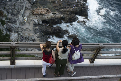 Rear view of women standing by railing against mountain