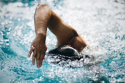 Midsection of man swimming in pool