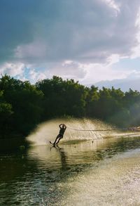 Man waterskiing on lake against sky