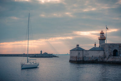 Sailboats sailing on sea against sky during sunset