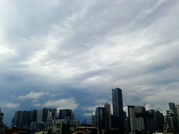 Skyscrapers in city against cloudy sky