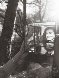 Portrait of young woman standing on tree trunk