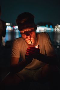 Close-up of young man holding camera at night