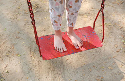 Low section of woman girl standing on swing at playground