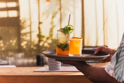 Cropped hand of woman holding drink on table