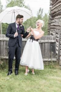 Smiling couple with umbrella standing on lawn