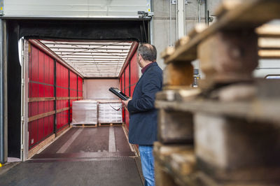 Manager checking goods in storage hall of factory