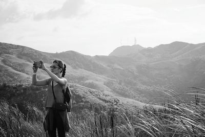 Woman photographing with mobile phone on landscape