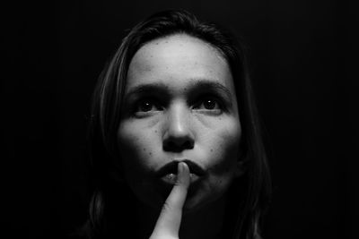 Portrait of young woman against black background