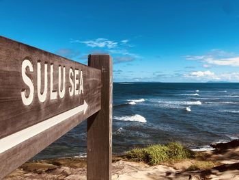 Information sign on beach against sky