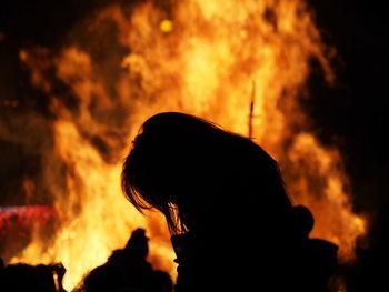 Side view of silhouette woman against bonfire at night