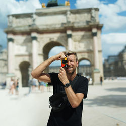 Man photographing with camera while standing on mobile phone