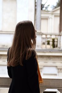 Rear view of woman standing in front of building