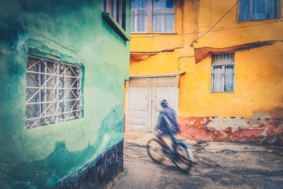 Man riding bicycle on street against building