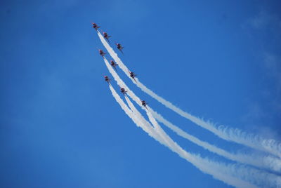 Low angle view of vapor trails against blue sky