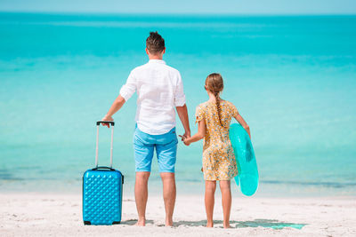 Rear view of father and daughter standing on beach