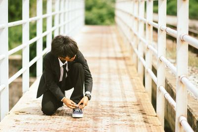 Full length of man sitting on footpath