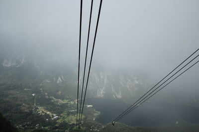 Low angle view of overhead cable car against sky