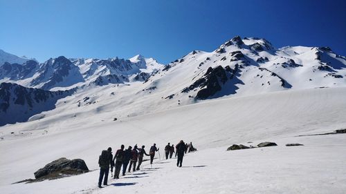 People on snowcapped mountain against clear sky