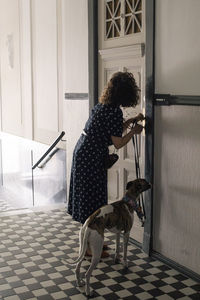 Woman locking house door while standing with dog