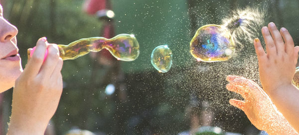 Panoramic image of playful mother blowing bubbles with child