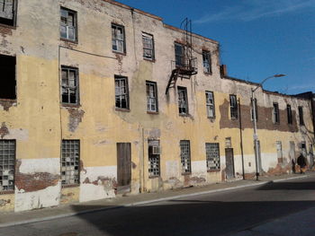 Empty road by buildings against sky in city