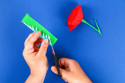 Close-up of hand holding paper over blue background