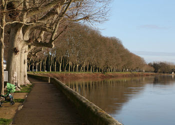 Footpath by lake against sky