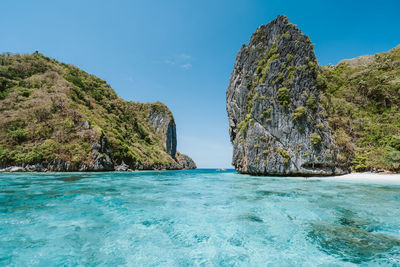 Rock formations in sea against blue sky