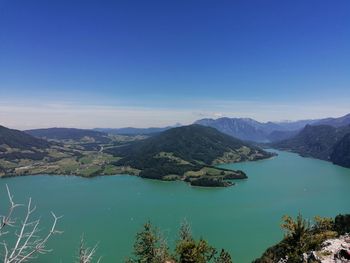 Scenic view of lake and mountains against clear blue sky