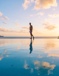 Rear view of woman walking at beach against sky