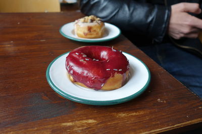 Cropped image of man with donut in plate on table